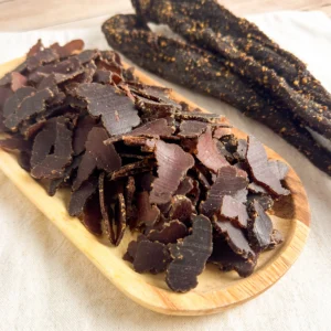 Kudu biltong sliced and whole on a wood cutting board top angle view