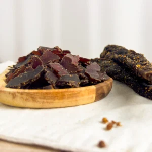 Kudu biltong sliced and whole on a wood cutting board angle view