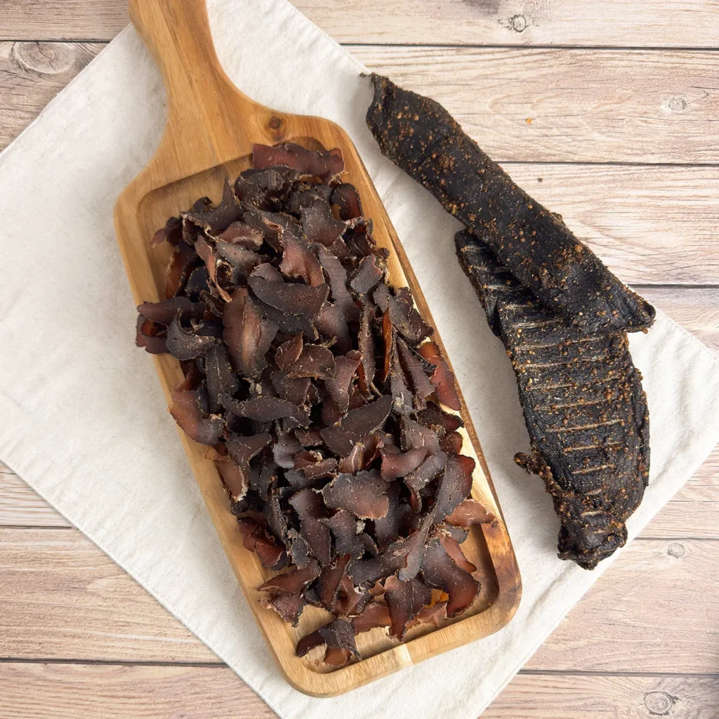 springbok biltong whole and sliced on wood cutting board main image