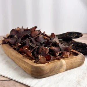 springbok biltong whole and sliced on wood cutting board angle view