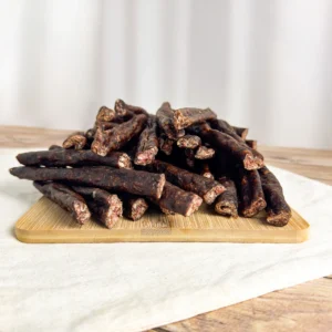springbok droewors pieces on a wood cutting board , side view